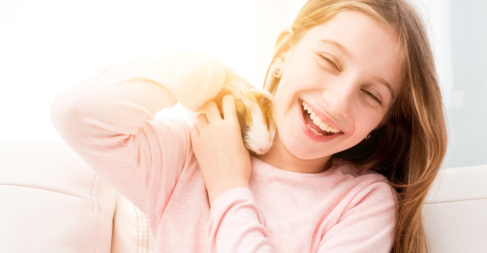 Girl feeling ticklish and laughing with guinea pig on her neck